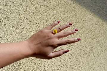 The hand of a woman wearing a flower as a ring on her finger.