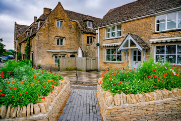 Flowers bloom in front of buildings in a small country village in England - 619646931