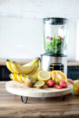 Blender with ingredients for smoothie and products on wooden table in kitchen