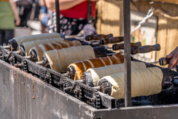 Fully baked and half baked chimney cake rolls at a market, popular street food no people - obrazy, fototapety, plakaty