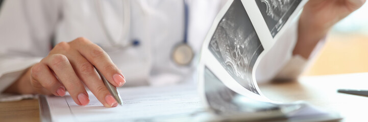 Female doctor looking at description of ultrasound shots of patient