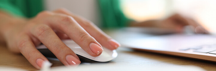 Woman using computer mouse working on modern laptop in office