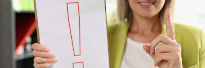 Smiling woman holding clipboard with red exclamation point