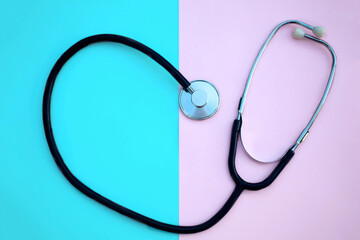 Heart shaped stethoscope, on a pink and blue background. Copy space.