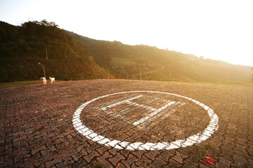 Helicopter landing symbol on concrete floor with natural sunset on the mountain.