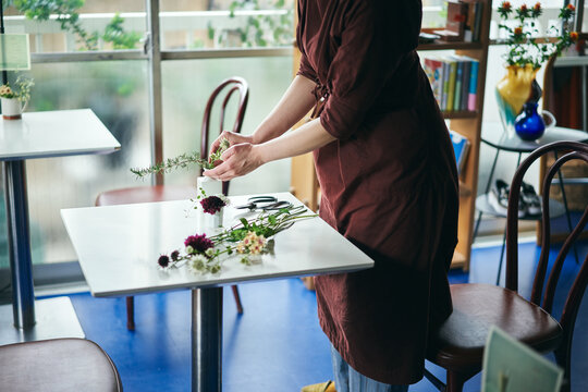 開店前のカフェで花をいける日本人女性