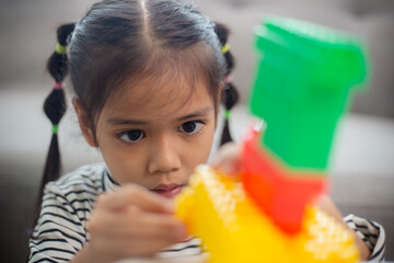 Adorable little girl playing toy blocks in a bright room.