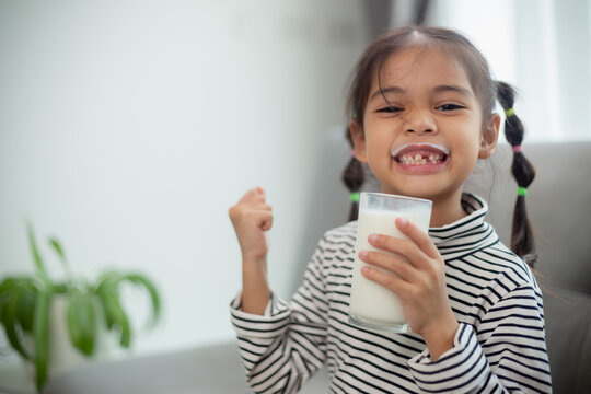 Asian little cute kid holding a cup of milk in the house. feel happy and enjoy drinking milk.