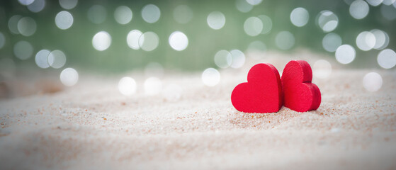 Two Wooden Red Hearts On sandy beach With Light Bokeh, The Concept of Love and Couple. Valentine's Day Concept.