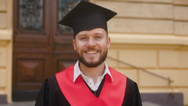 Students celebrate graduation. Portrait of young man dressed in gown and graduation cap.