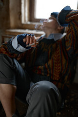 Fototapeta na wymiar Girl in old dirty, ragged clothes smoking cigarette, selective focus
