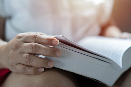 Cropped image hand of old woman opening and reading a book