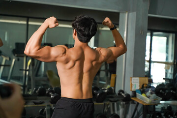 Fototapeta na wymiar Closeup back view perfect body of Asian guy in fitness center.