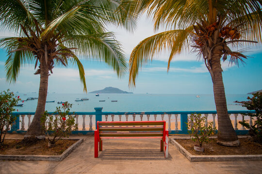 Tropical dreams, picturesque palms surrounding a red bench with a view towards an islands and a beach with boats. Beautiful destination photo, travel lust, wanderlust, Taboga island, panama