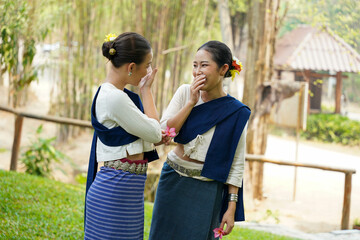 Closeup a beautiful Thai young lady ware Thai northern traditional dress chatting and teasing each other on blurred background.