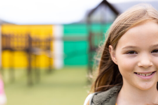 Portrait of smiling caucasian schoolgirl in schoolyard, with copy space