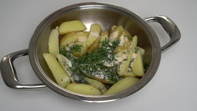 The cook puts the hot tabasco sauce in the pot with the sliced potatoes. Side view. Process and recipe for rustic or Idaho potatoes. Step by step. Step 11.