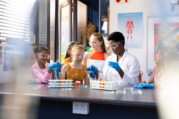 Diverse female teacher and schoolchildren doing an experiment in chemistry class