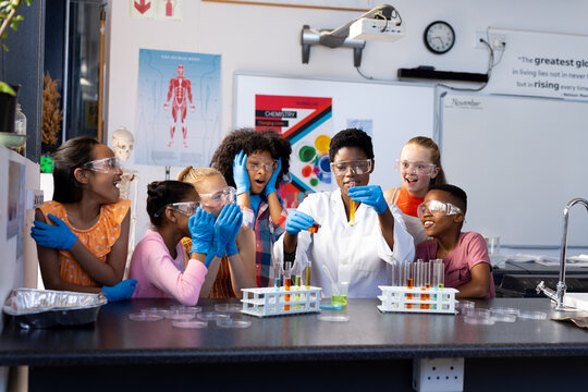 Diverse female teacher and excited school children doing experiment in chemistry class