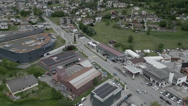 Aerial shot of the city of Brig - Glis in Switzerland. Traffic driving on the road. Industrial building, gas station and Migros