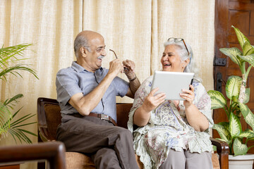 Happy Indian Grey hair Senior couple sitting at sofa in Living room and enjoying life