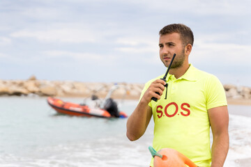 Lifesaver standing on the sea water using a radio