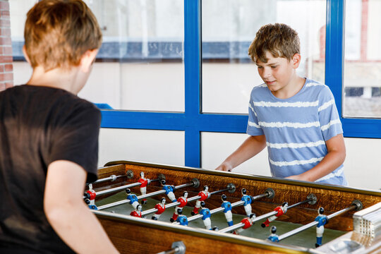 Two smiling school boys playing table soccer. Happy excited children having fun with family game with siblings or friends. Positive preteen kids or teenager.