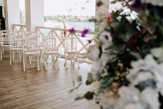 Chairs for Guests Standing on Restaurant Terrace Photography. Seats Wooden Furniture for Audience Staying on Cafe Parquet And Blooming Fresh Flowers. Stylish Interior Decorated Bouquet