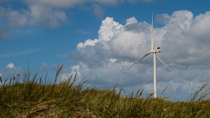 Windrad steht an der Küste in den Dünen und erzeugt Energie durch Wind