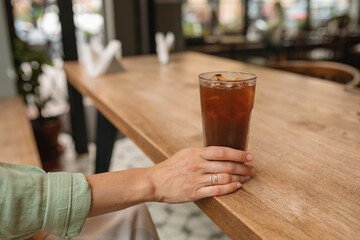 Refreshment summer drink with tonic water, lemon and coffee in tall glass on the table in cafe.