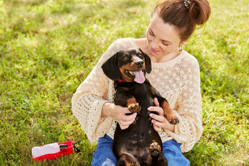 young girl hugging a dachshund dog in the park on a sunny day, the concept of animal care
