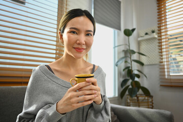 Relaxed woman drinking hot coffee, spending free time in Sunday morning at home