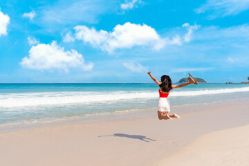 Happy young Asian female relax smile around beautiful tropical sea beach ocean with white cloud on blue sky in travel vacation. Summer and holiday concept. Free space