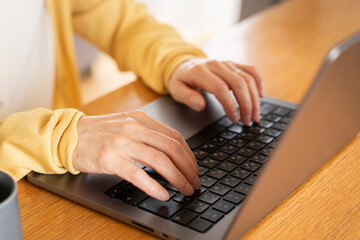 ノートパソコンをタイピングしているシニア女性