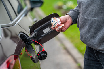 a man counts money standing at an open fuel tank, the concept of rising fuel prices, closeup