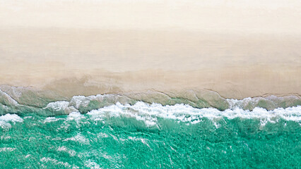 Beautiful quiet white beach background with emerald green ocean waters. Aerial view from above of sea and sand.