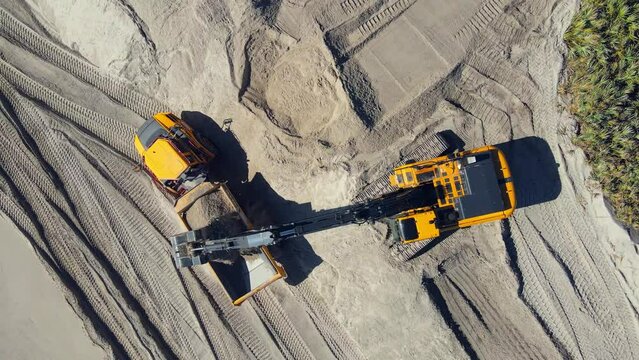 4k drone shot of excavators working on the beach near the ocean water with tropical greenery near by.