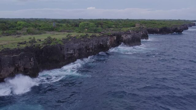 Drone flies along clif with small waves at Sumba Indonesia, aerial