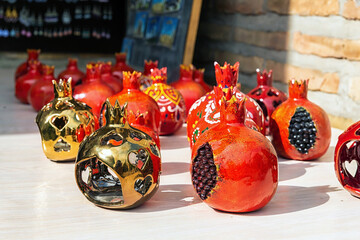 Red and gold pomegranates. Traditional ceramics, typical handicraft souvenir in street market. Souvenir and gift concept. April 10, 2023. Tashkent, Uzbekistan