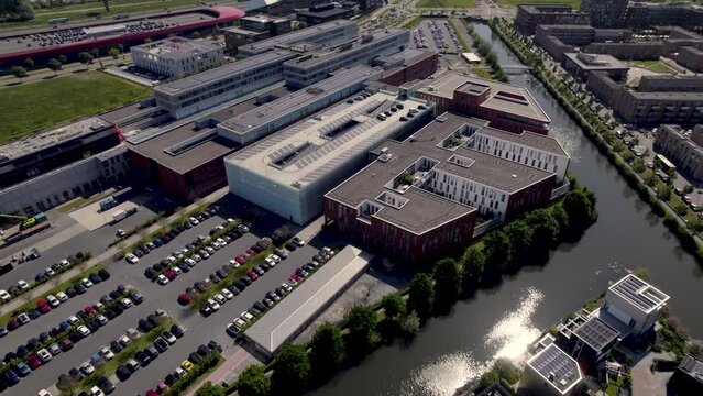 Aerial rotating pan showing Dutch Antonius hospital surrounded by water in city of Utrecht with 'The Wall' shopping in the background in contemporary Leidsche Rijn neighbourhood.