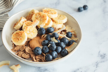 Wholegrain breakfast cereal with banana, coconut and blueberries. Vegan breakfast concept.