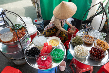 A Vietnamese woman preparing street food in a small street cafe.