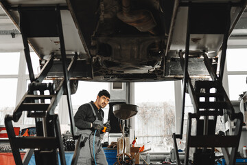 Fototapeta na wymiar Workman mechanic working under car in auto repair shop