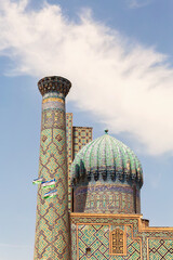 Obraz premium Sher-Dor Madrasah and national flags at the Registan square. A Unesco World Heritage Site. Vertical shot. Samarkand. Uzbekistan