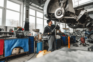 Auto mechanic repairs running gear of a car in car service