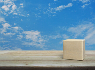 Wood block cube on wooden table over blue sky with white clouds