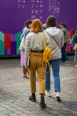 View from behind young girls walking together at city exhibition. Regular people out in public...