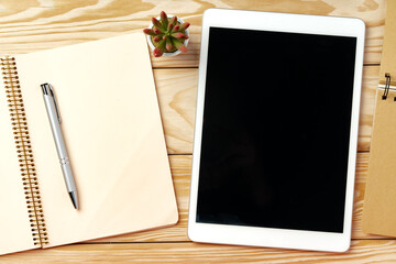 Top view of wooden table with white digital tablet with black screen on it