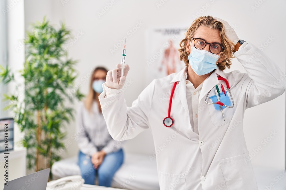 Canvas Prints Blond man wearing doctor uniform and medical mask holding syringe stressed and frustrated with hand on head, surprised and angry face