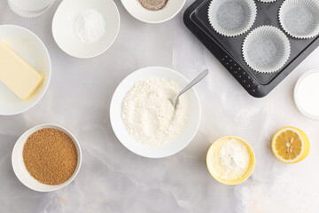 Various baking ingredients - flour, sugar, butter and kitchen utensils on grey background. Top view.